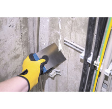 Artisan enduisant un mur avec une spatule.