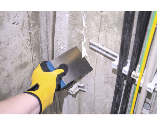 Artisan enduisant un mur avec une spatule.