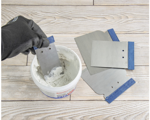 Du mastic est retiré d''un seau avec une spatule, d''autres spatules sont prêtes