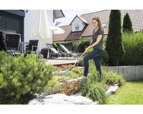 Frau arbeitet mit einem Rechen im Garten.
