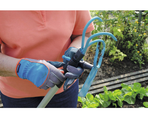 Person mit Gartenhandschuhen hält eine Hacke