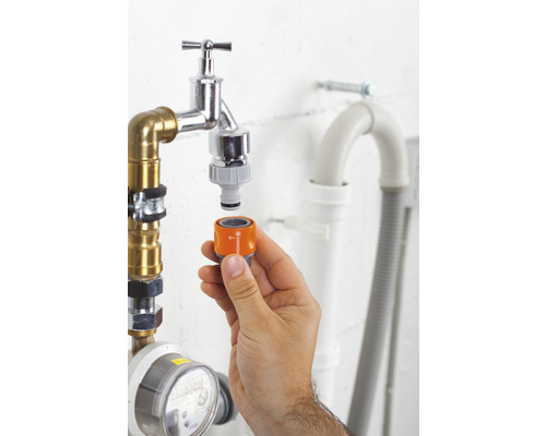 Main fixant l''adaptateur Gardena au robinet pour l''irrigation du jardin
