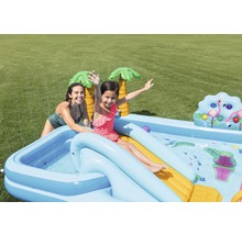 Pataugeoire gonflable avec toboggan et arroseur pour enfants dans le jardin avec deux personnes qui jouent.