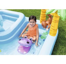 Fille jouant dans une pataugeoire gonflable avec toboggan, palmier et singe