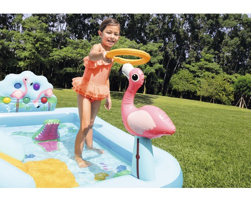Enfant jouant avec pataugeoire gonflable avec motif flamant rose dans le jardin