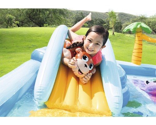 Enfant glissant sur un toboggan aquatique gonflable avec motif de singe dans la pataugeoire