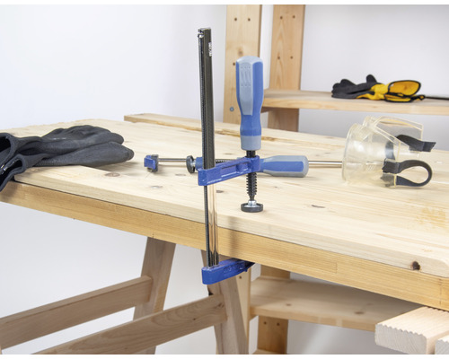 Werkbank mit Schraubzwinge, Schutzbrille und Arbeitshandschuhen