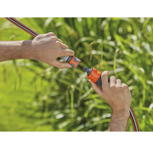 Deux mains raccordent un tuyau d''arrosage à un raccord de tuyau.