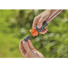 Personne raccordant un tuyau d''arrosage à un raccord de tuyau