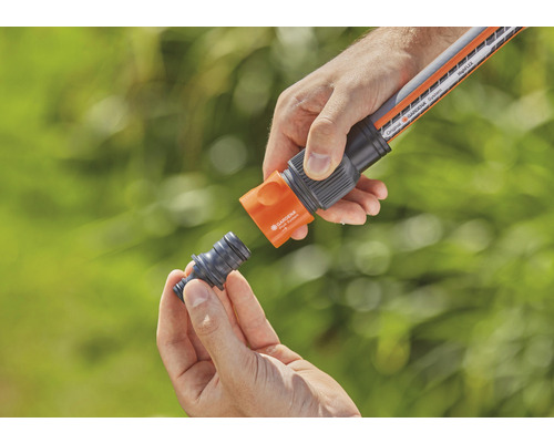 Personne raccordant un tuyau d''arrosage à un raccord de tuyau