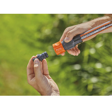 Une personne connecte un raccord de tuyau d''arrosage à un tuyau d''arrosage