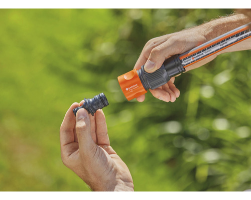 Une personne connecte un raccord de tuyau d''arrosage à un tuyau d''arrosage