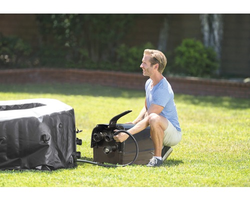 Mann schliesst Pumpe an aufblasbaren Whirlpool im Garten an