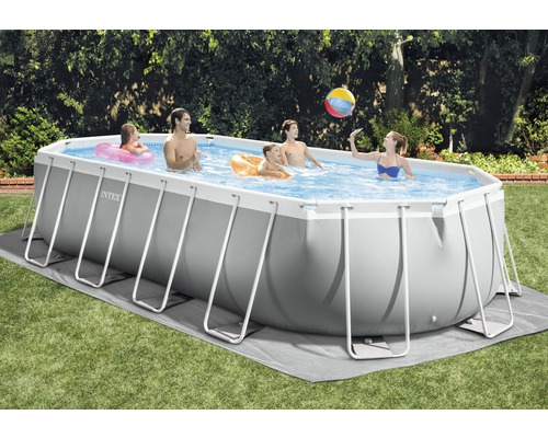 Une famille nage dans une piscine Intex rectangulaire dans le jardin.