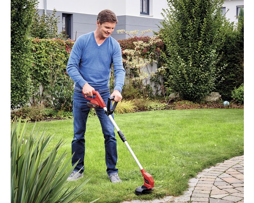 Un homme utilise un coupe-bordures à batterie dans le jardin.