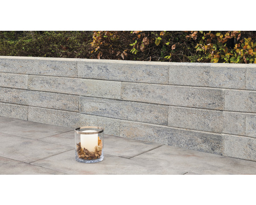 Muret de jardin en pierre avec bougie décorative dans un verre