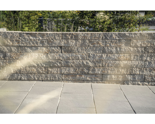 Un mur en blocs de pierre et un sol en dalles de pierre à l''extérieur.