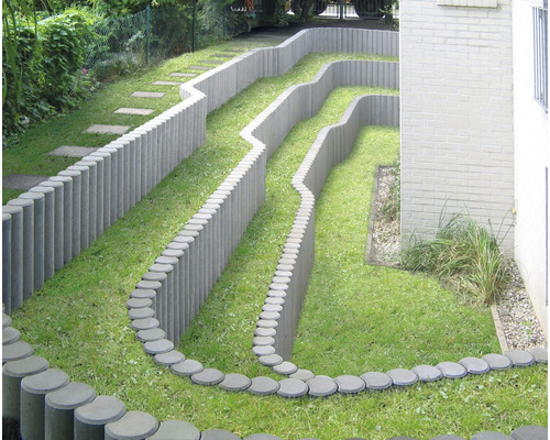 Jardin en terrasses avec pelouse et bordures de parterres en palissades de béton