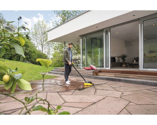 Un homme nettoie une terrasse avec un nettoyeur de terrasse