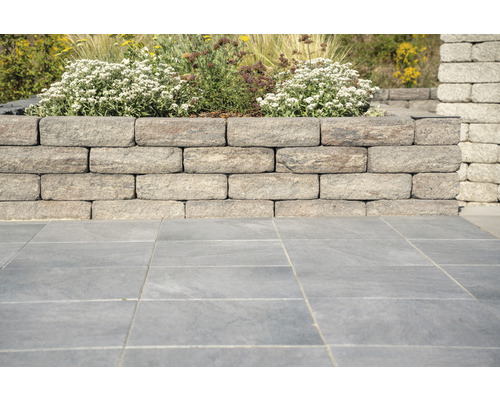 Muret de jardin en blocs de pierre avec fleurs et pavés