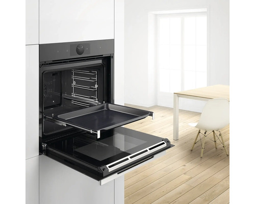 Four encastrable avec porte ouverte, plaque de cuisson et éclairage intérieur dans une cuisine lumineuse