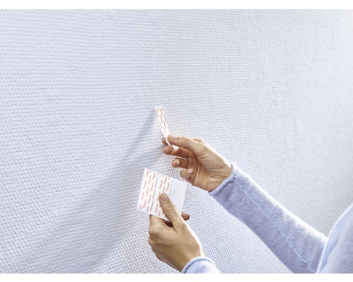 Personne fixant des bandes adhésives sur un mur