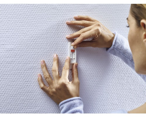 Femme fixant un crochet adhésif au mur