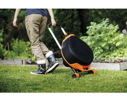 Person zieht einen mobilen Gartensitzwagen über einen Rasen.