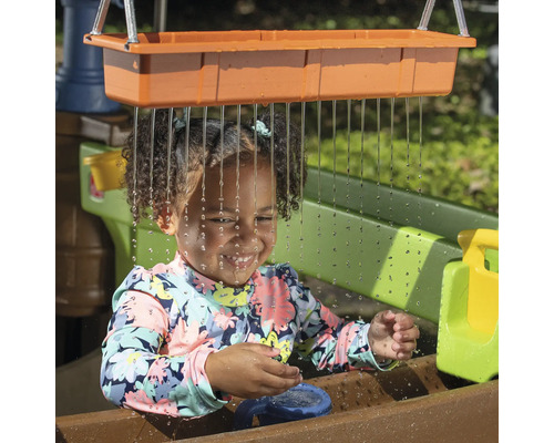Fille jouant avec une table de jeu d''eau dans le jardin