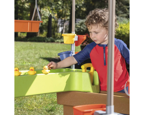 Un enfant joue avec une table de jeu d''eau et des canards jaunes dans le jardin.