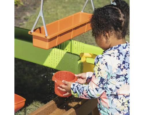Enfant jouant avec un circuit d''eau dans le jardin