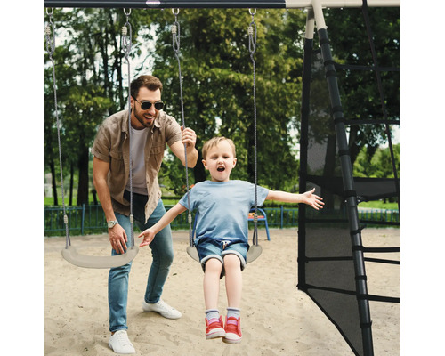 Un père pousse son enfant sur une balançoire d''une tour de jeu.