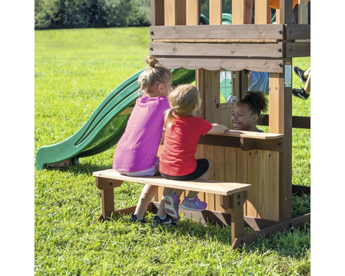 Trois enfants jouent sur une aire de jeux en bois avec toboggan et banc