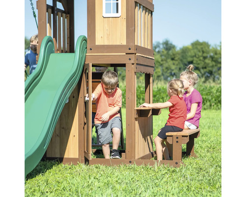 Cabane de jeu en bois avec toboggan et table avec banc dans le jardin