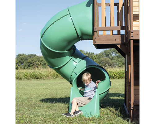 Garçon sur un toboggan tunnel vert dans une aire de jeux