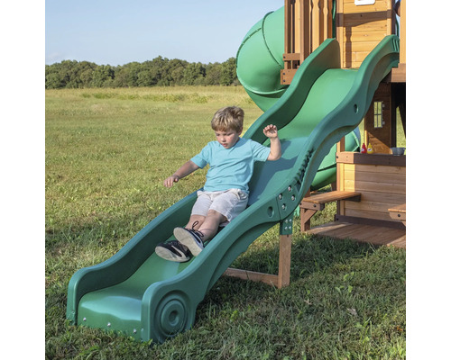 Garçon glissant sur un toboggan vert pour enfants.