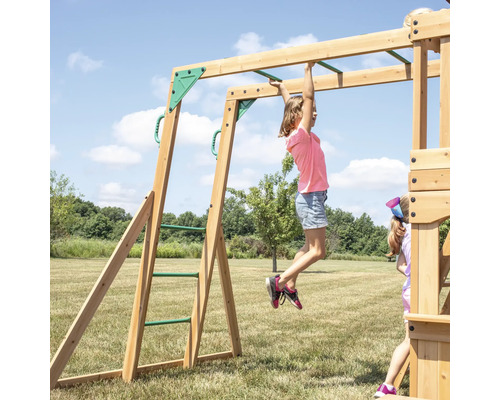 Un enfant est suspendu à une balançoire en bois avec une échelle à barreaux dans le jardin.