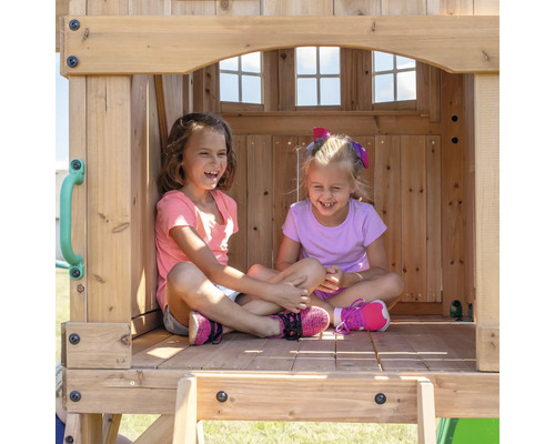 Deux filles souriantes sont assises dans une cabane en bois.