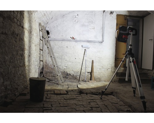 Cave avec échelle, seau, rouleau à peinture et projecteur de chantier sur trépied