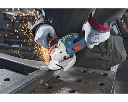 Une personne utilise une meuleuse d'angle sans fil pour couper du métal, produisant des étincelles.