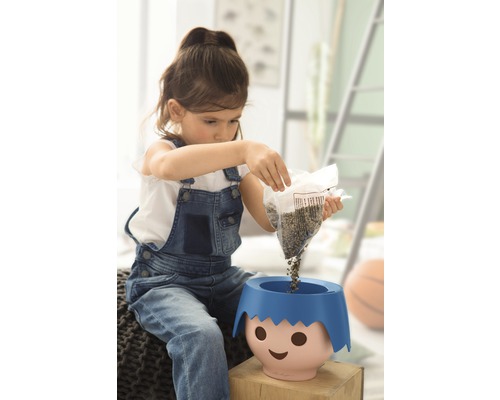 Une fille verse des graines dans un pot de fleurs avec un visage