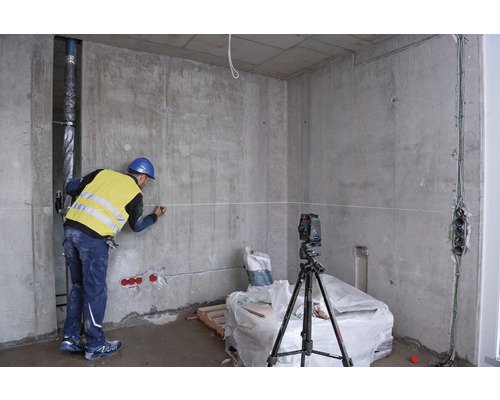 Bauarbeiter markiert Wand mit Laser-Wasserwaage in einem Rohbau