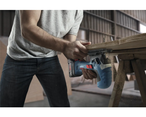 Une personne coupe du bois avec une scie sauteuse sans fil.