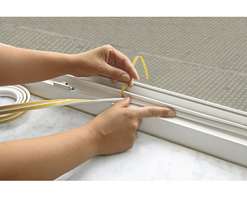 Une personne pose un joint autocollant sur une fenêtre.