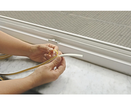 Les mains retirent le film protecteur de la bande d''étanchéité sur la fenêtre