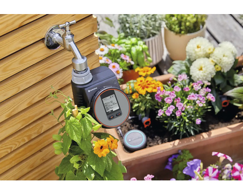 Robinet Gardena avec programmateur d''arrosage dans un jardin fleuri