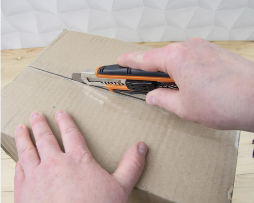 Un carton est ouvert avec un cutter.