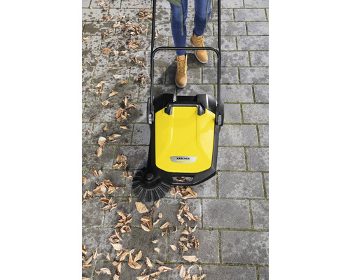 Balayeuse jaune en action pour enlever les feuilles sur une surface pavée