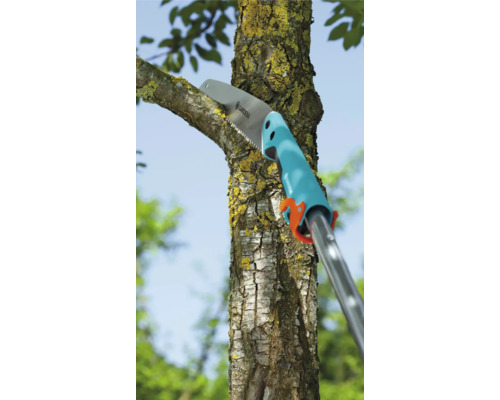 Une scie à branches coupe une branche sur un arbre.