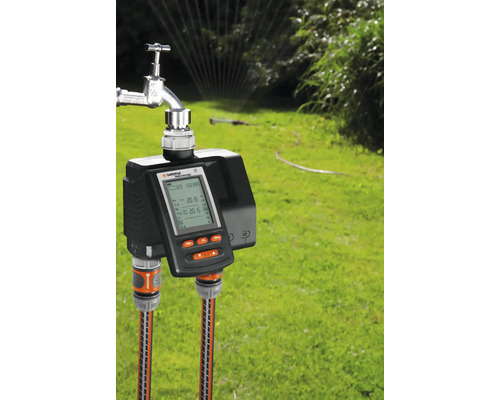 Programmateurs d''arrosage Gardena sur le robinet avec deux tuyaux d''arrosage dans le jardin.